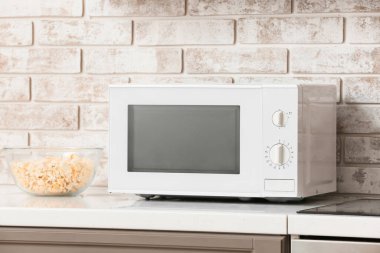 Mikrodalga fırın ve patlamış mısırla birlikte hafif tuğla duvarın yanında.