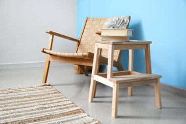 Dekorlu, kitaplı ve mavi duvarın yanındaki koltuklu ahşap basamak.