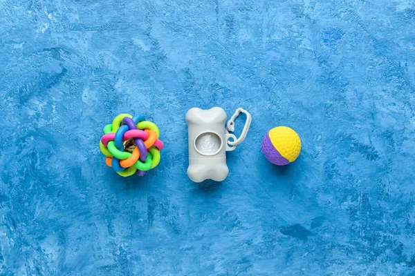 Dispenser with pet waste bags and rubber balls on blue background