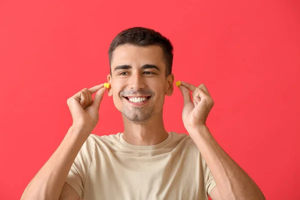 Sorrindo Jovem Colocando Tampões Ouvido Fundo Vermelho — Fotografia de Stock