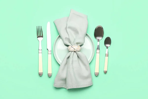 Set of cutlery, plate and napkin on color background