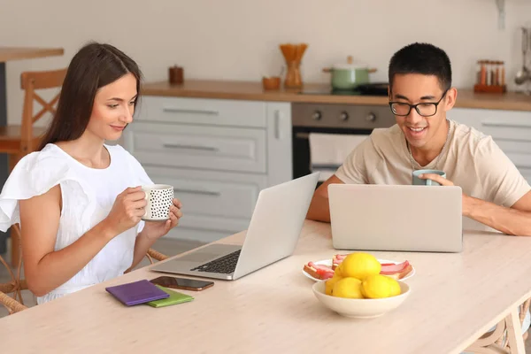 Jovem Casal Com Xícaras Café Usando Laptops Mesa Cozinha — Fotografia de Stock