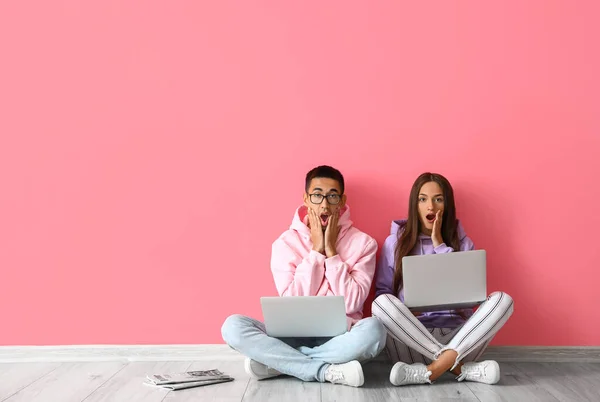 Schockiertes Junges Paar Sitzt Mit Laptop Pinkfarbener Wand — Stockfoto