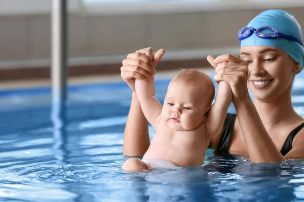 教小宝宝如何在游泳池里游泳的年轻女人 — 图库照片