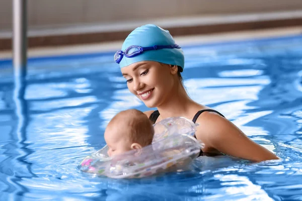 年轻女子和她可爱的小宝宝带着充气环在游泳池里 — 图库照片