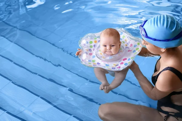 年轻妈妈和她可爱的小宝宝带着充气环在游泳池里 — 图库照片
