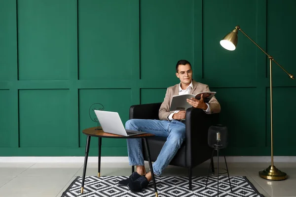 Young Man Eyeglasses Reading Magazine Leather Armchair Green Wall — Stock Photo, Image