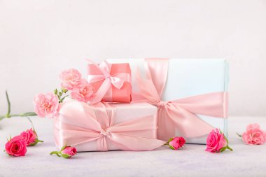 Güzel çiçekler ve açık arkaplanda hediye kutuları