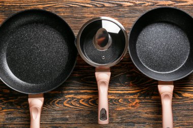 Ahşap arka planda kızartma tavaları ve tencereler