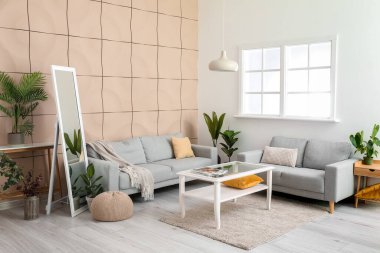 Rahat kanepeleri, aynaları ve çiçekleri olan şık bir oturma odası.