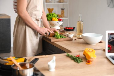 Genç adam mutfakta video dersini takip ederken marul kesiyor.