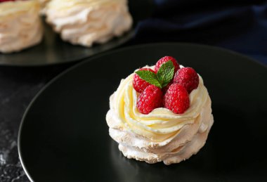 Koyu arkaplanda taze böğürtlenli lezzetli Pavlova pastası.