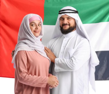 Geleneksel giyinmiş ve beyaz arka planda BAE bayrağı olan bir çift.