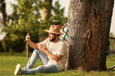 Bisikletli yakışıklı sakallı adam parkta sohbet ediyor.