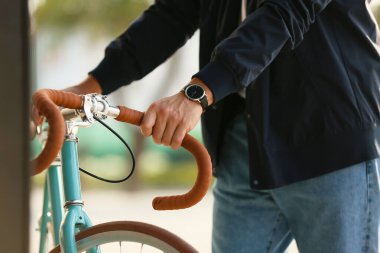 Şehirde bisikletli şık genç adam, yakın plan.