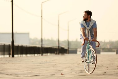 Kum seti üzerinde bisiklet süren yakışıklı sakallı adam