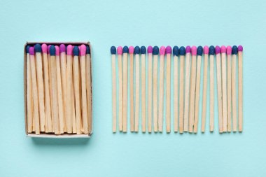 Mavi arkaplanda farklı yeni kibrit çöpleri olan kutu