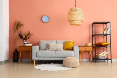 Kanepesi, ahşap masaları ve raf ünitesi olan şık bir oturma odası.