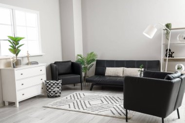 Siyah koltukları ve kanepesi olan modern oturma odasının içinde.