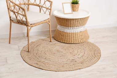 Hasır koltuklu, masalı ve ahşap zeminde şık bir halısı olan bir oda.