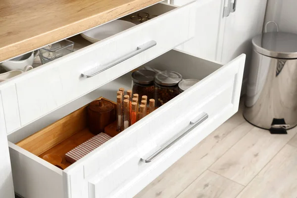 Opened drawers with spices and utensils in modern kitchen