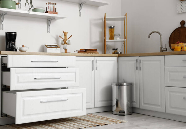 Современные прилавки с открытыми ящиками и мусорным баком в кухонном интерьере