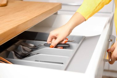 Mutfaktaki çekmeceden kaşık alan kadın, yakın plan.