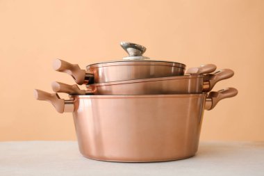 Masada bej arka planda parlak tencereler