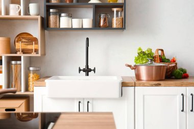 Işık duvarının yanındaki tezgahta taze sebzelerle dolu parlak bir tencere ve sepet.