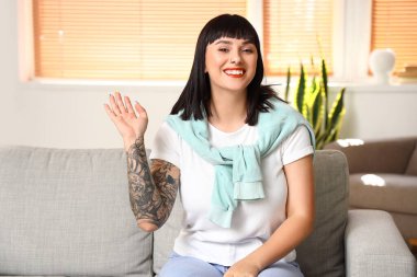 Dövmeli genç kadın evde video sohbeti yapıyor.