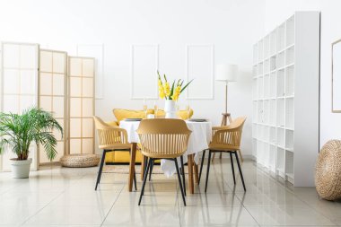 Işıl ışıl yemek odasının içinde güzel masa düzeniyle ve içinde Gladiolus çiçekleri olan vazo