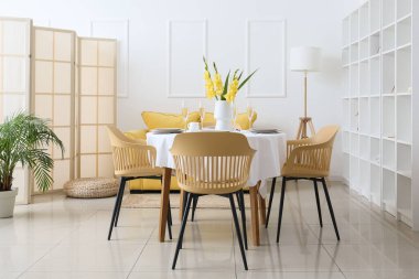 Işıl ışıl yemek odasının içinde güzel masa düzeniyle ve içinde Gladiolus çiçekleri olan vazo