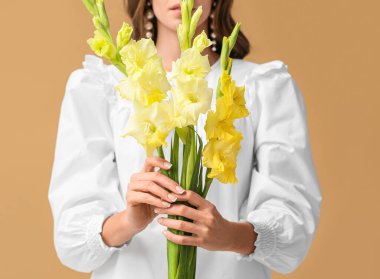 Renkli arka planda bir buket Gladiolus çiçeği tutan şık bir kadın, yakın plan.