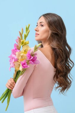 Renkli arka planda bir buket Gladiolus çiçeğiyle zarif bir kadın.