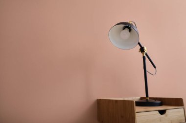 Bej duvarın yanında siyah lambalı ahşap masa.