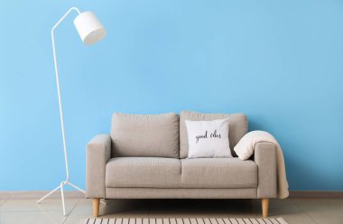 Mavi duvarın yanında beyaz lamba ve kanepe.