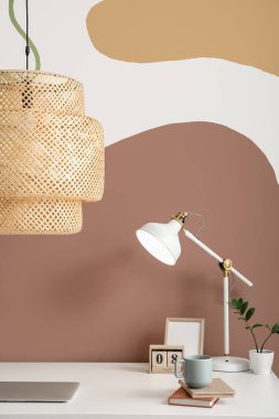 Renk duvarına yakın dizüstü bilgisayarı ve lambaları olan modern işyeri