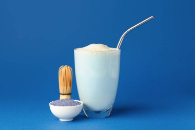 Bir bardak lezzetli mavi kibrit sütlü latte, arkaplanda toz ve kase.