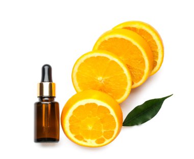 Beyaz arka planda bir şişe gerekli yağ ve taze kesilmiş turuncu.