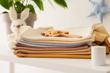 Bebek kıyafetleri yığını ve çıngırak, yakın çekim.