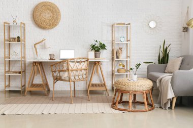 Işık odasının içinde beyaz tuğla duvarın yanında dizüstü bilgisayarı olan işyeri