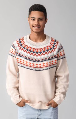 Hafif arka planda örgü süveter giyen yakışıklı Afro-Amerikalı adam.