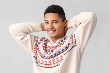 Hafif arka planda örgü süveter giyen yakışıklı Afro-Amerikalı adam.