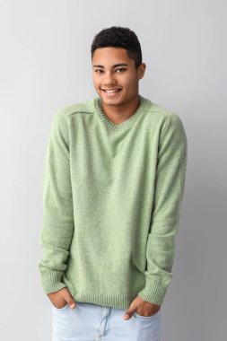 Hafif arka planda örgü süveter giyen yakışıklı Afro-Amerikalı adam.