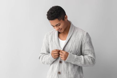 Hafif arka planda örgü süveter giyen yakışıklı Afro-Amerikalı adam.