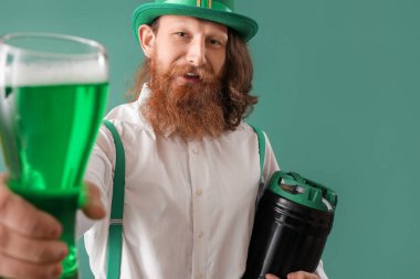 Yeşil arka planda bir bardak birası ve fıçısı olan mutlu sakallı adam. Aziz Patrick Günü kutlaması