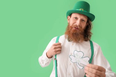 Elinde kağıt yonca tutan sakallı bir adam yeşil arka planda PATRICK Günü.