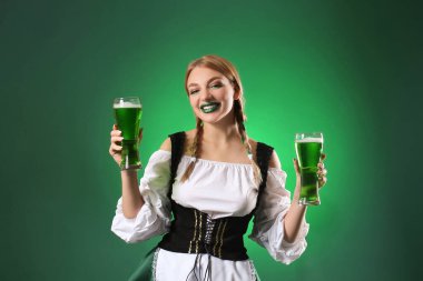 Yeşil arka planda bira bardakları olan güzel bir İrlandalı garson. Aziz Patrick Günü kutlaması