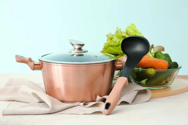 Shiny Cooking Pot Ladle Bowl Vegetables Table Blue Background — Stock Photo, Image