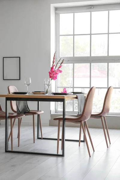 ダイニングテーブルとグラジオラスの花を提供するモダンな光の部屋のインテリア — ストック写真